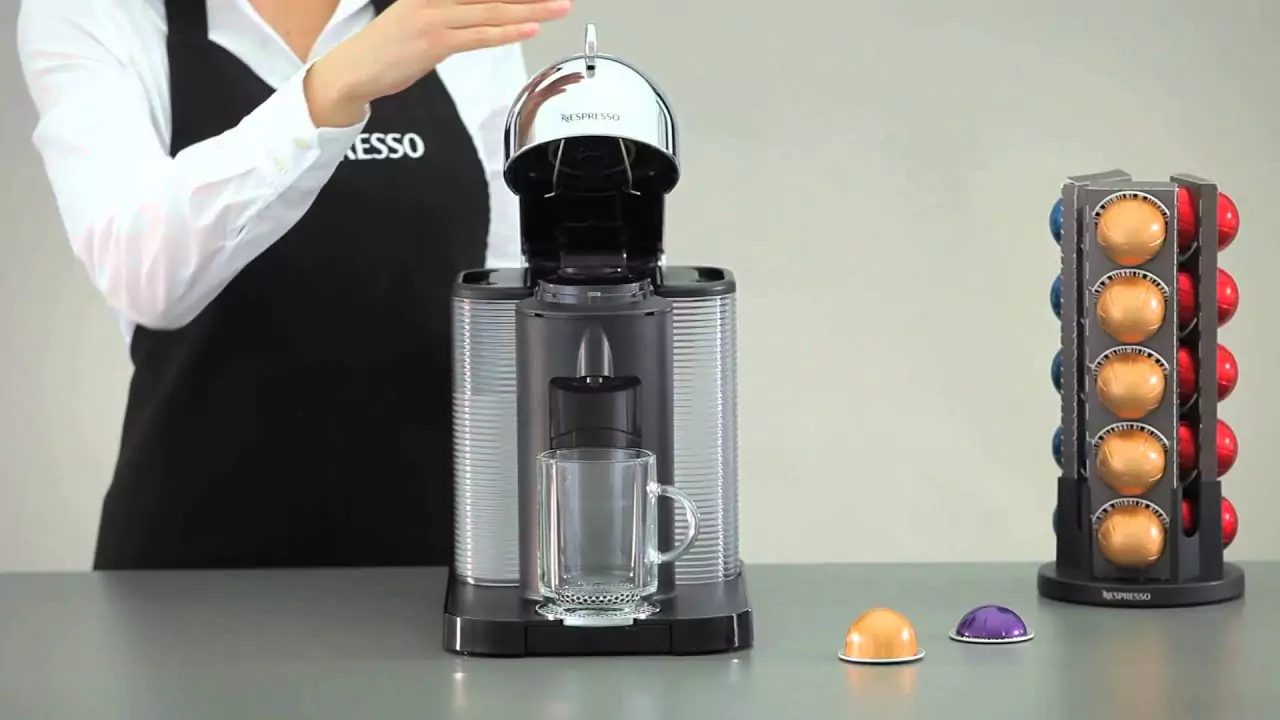 someone using the nespresso machine, the person is wearing a black apron. The nespresso machine is on the kitchen counter 