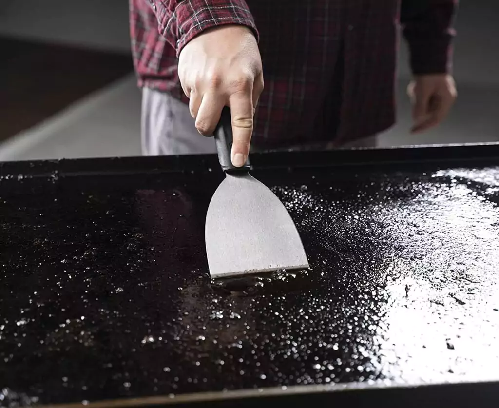 removing food debris from a grill with a grill scraper