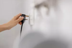 Woman's hand about to plug an electrical plug into an outlet