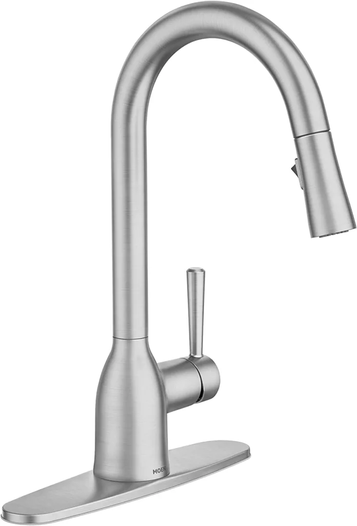 A Moen Adler Spot Resist Stainless Kitchen Faucet with a sleek, curved design and a single handle, set against a white background. The faucet has a tall, arched spout that is capable of swiveling, providing ample space for washing dishes or filling pots. It features a single lever handle on the side for easy control of water flow and temperature. The faucet’s spot resist stainless finish helps in reducing fingerprints and water spots for a cleaner look. It is mounted on an escutcheon plate which aids in its installation on the kitchen sink.
