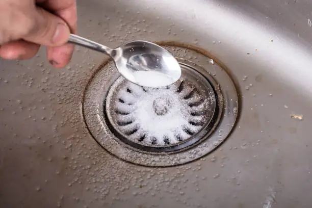  “A person pouring salt into a sink drain for cleaning purposes”