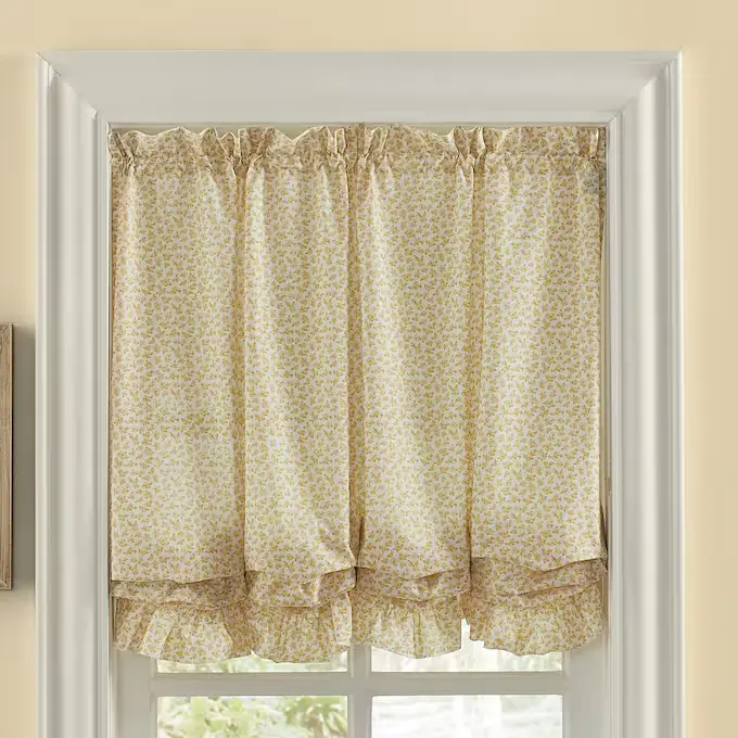 A window adorned with elegant balloon shades featuring a subtle floral pattern, casting a soft light into the room.
