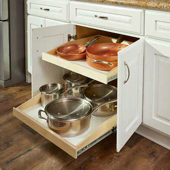 A well-organized kitchen cabinet with pull-out shelves containing neatly arranged pots and pans.
