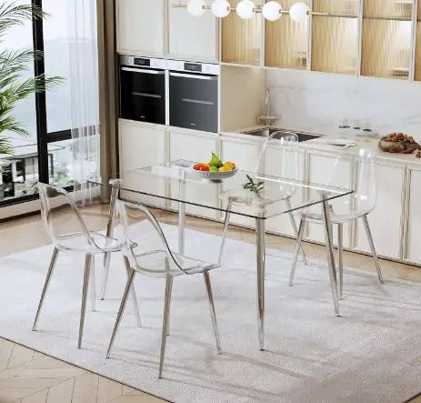 Lucite dining table in front of a small kitchen, the cabinets are white in color