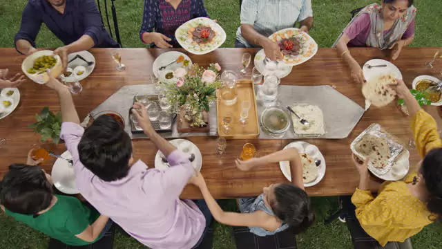 A group of people gathered around a table, enjoying a meal outdoors.
