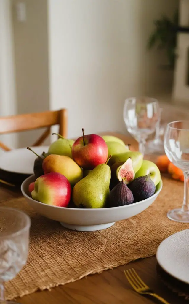 A dining table featuring a bowl of seasonal fruits like apples, pears, and figs as part of the fall decor. The fruits add vibrant colors and a natural, edible element to the table setting.