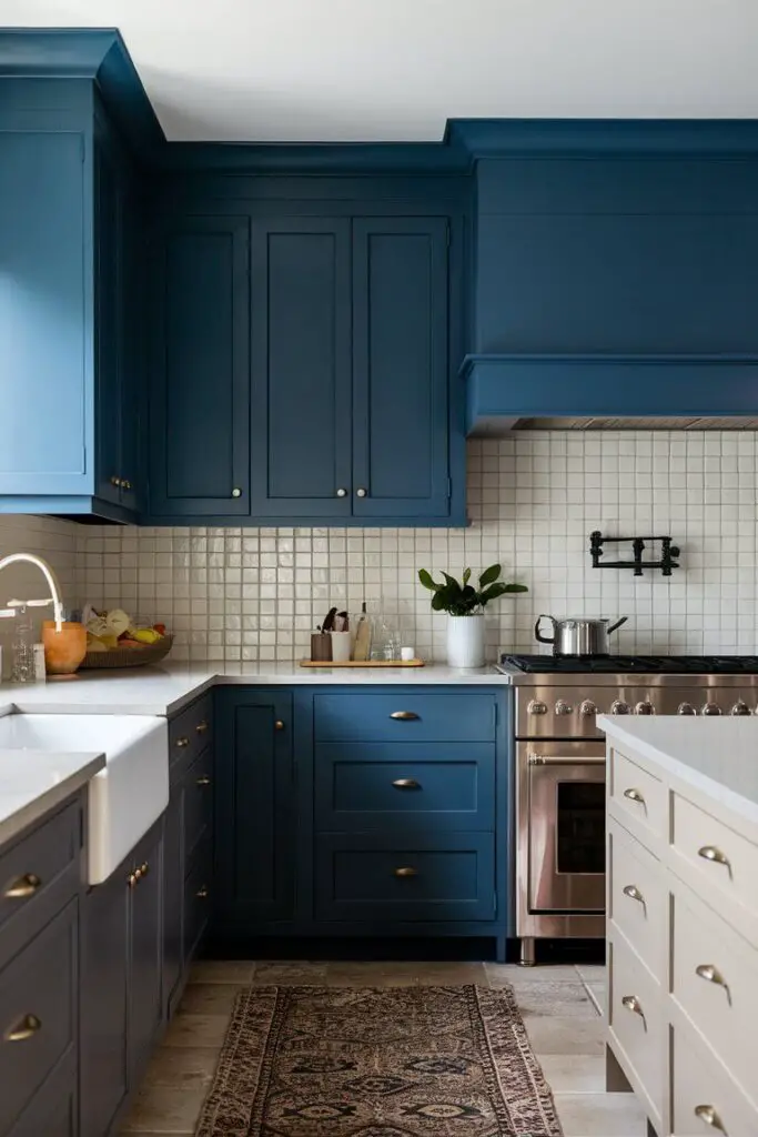 A kitchen with deep blue cabinets, paired with neutral countertops and a white tiled backsplash. The bold cabinet colors create a striking contrast, showcasing one of the many Colorful Eclectic Kitchen Ideas for a dynamic and lively space.