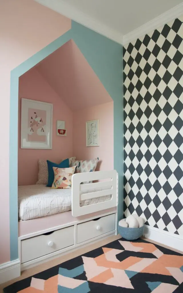 A photo of a small toddler bedroom with different paint colors to define various zones. The sleep area, featuring a cozy toddler bed design, is framed by soft pastel paint. The play zone is accented by bold geometric wallpaper. The clever use of paint visually separates play from rest.