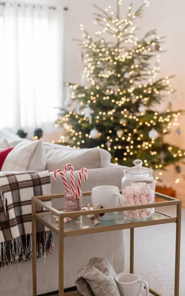 A photo of a Christmas living room with a charming mini hot cocoa station set up on a sleek bar cart. The cart is minimalist decorated with candy canes, marshmallows in a jar, and festive mugs. A very cozy sofa with a plaid throw and coordinating pillows is nearby, while a tall Christmas tree stands in the background, glowing softly in warm lights.