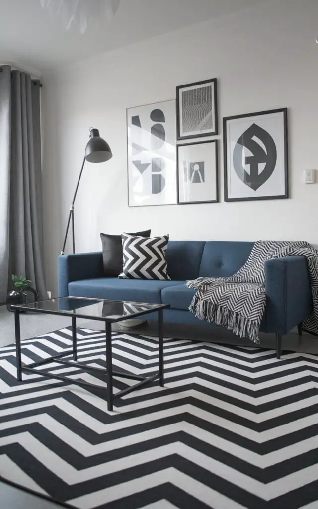 A photo of a modern living room with a chevron-patterned rug in bold black and white zigzags. The rug serves as a dynamic focal point. A blue sofa with monochrome throw pillows and a geometric throw blanket sits in front of the rug. A minimalist coffee table with a glass top is placed near the sofa. A black floor lamp and framed art prints adorn the room, adding trendy touches. The room has a cohesive and stylish look.