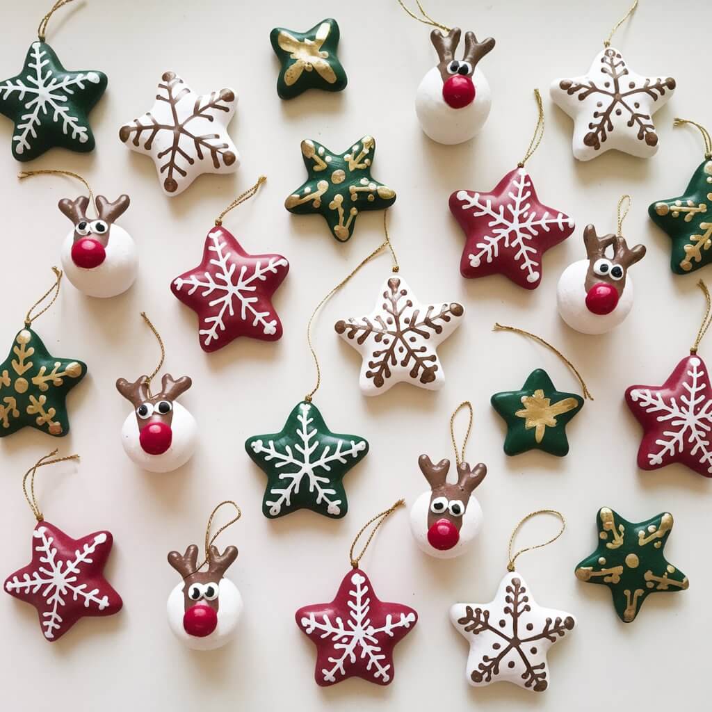 A photo of a plain white table with a delightful assortment of clay homemade simple-looking clay Christmas ornaments. There are stars, snowflakes, and reindeer-shaped ornaments. Each ornament is painted in festive colors of red, green, and white, with gold accents and small ribbons for hanging.