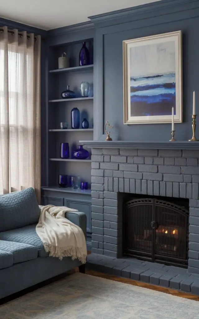 A photograph showcases a cozy living room scene dominated by a substantial grey stone fireplace. The fireplace is flanked by built-in shelves painted matte navy blue, displaying an assortment of ash and cobalt glass objects, with a framed abstract painting in layered blues and greys hanging above the mantel displaying "Hearthside Charm". A plush, storm-grey chenille sofa faces the hearth, adorned with a soft cream-colored throw blanket, inviting a sense of relaxation. Soft, warm light streams through sheer linen curtains, casting a gentle glow across the room and highlighting the brass candlesticks strategically placed on the mantel.